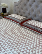 Bed with patterned bedding and tufted headboard in a bedroom setting