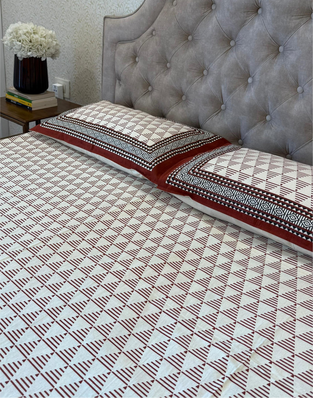 Bed with patterned bedding and tufted headboard in a bedroom setting